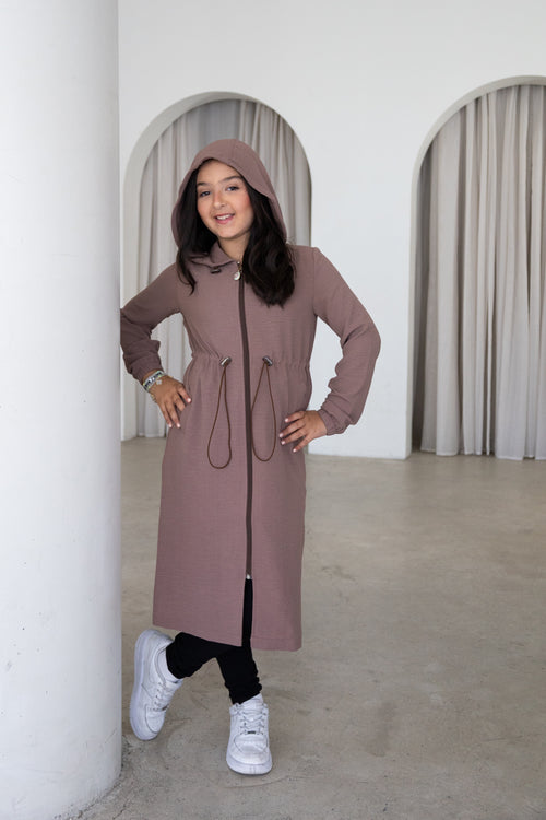 Elegant and modest, The Haya Coat is a timeless girls’ coat designed for comfort and effortless everyday style. Featuring a longline silhouette, hood, adjustable waist and versatile mocha colour, it’s the perfect layer for every occasion.