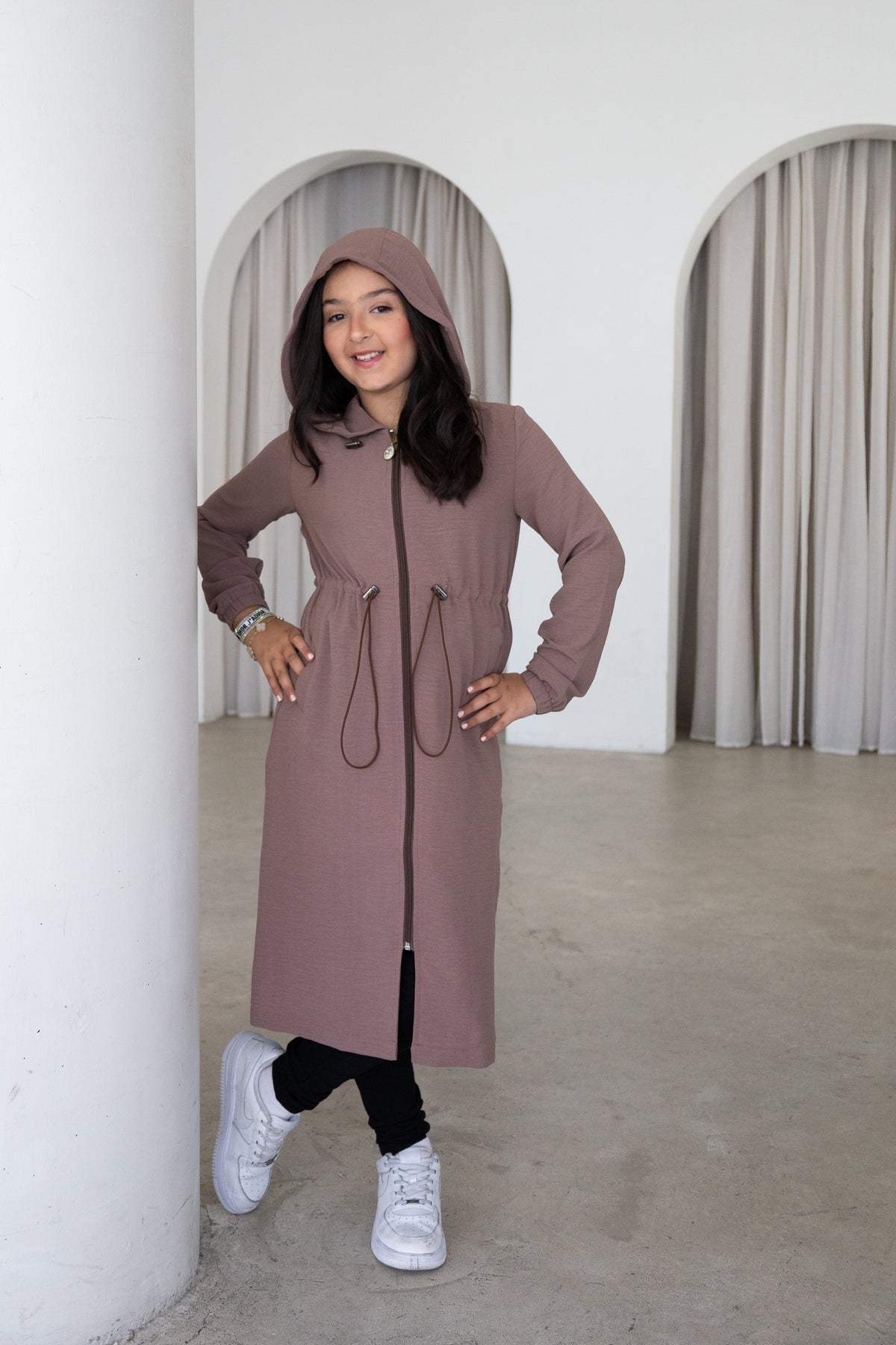 Elegant and modest, The Haya Coat is a timeless girls’ coat designed for comfort and effortless everyday style. Featuring a longline silhouette, hood, adjustable waist and versatile mocha colour, it’s the perfect layer for every occasion.